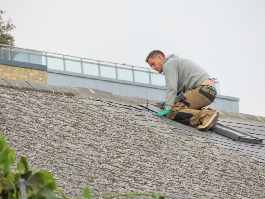 Handyman putting Roof Tiles on Roof