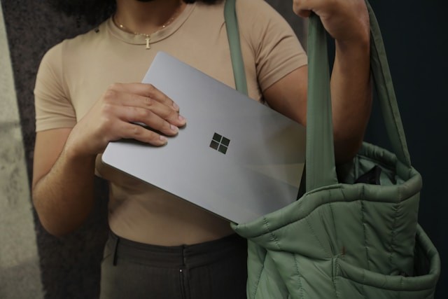 A photo depicting a woman packing up with her Microsoft laptop