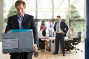 Business people watching smiling businessman leave office with box of belongings 