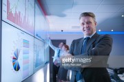 Company manager in front of graphs on screen in meeting room, portrait 