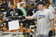 A production line worker moves a rear axle assembly of a 2014 Jeep Cherokee down the line at the upgraded North section of the Chrysler Toledo Assembly Complex which will be used to produce the new ve