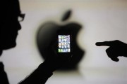 Men are silhouetted against a video screen with an Apple logo as they pose with an Apple iPhone 4 smartphone in this photo illustration taken in the central Bosnian town of Zenica, May 17, 2013. Credi