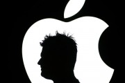 A man walks past an Apple logo 